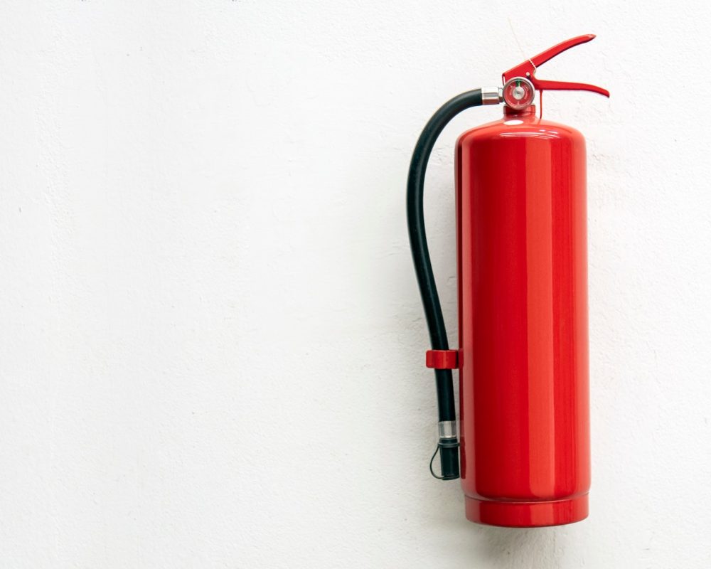 Fire extinguisher on white concrete wall for safety banner and background with copy space for text
